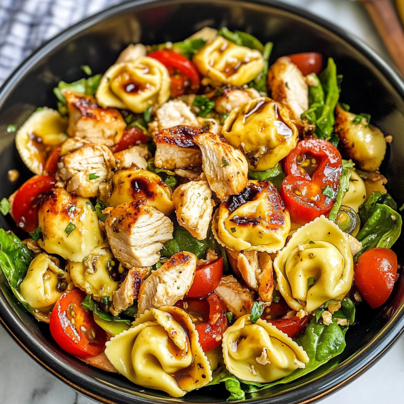 Une salade de poulet grillé avec des tortellini et des tomates.