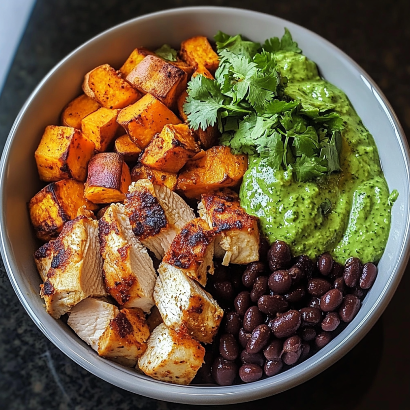 Un bol de nourriture contenant des chips de poulet grillé, des papas douces, des haricots noirs et du coriandre.