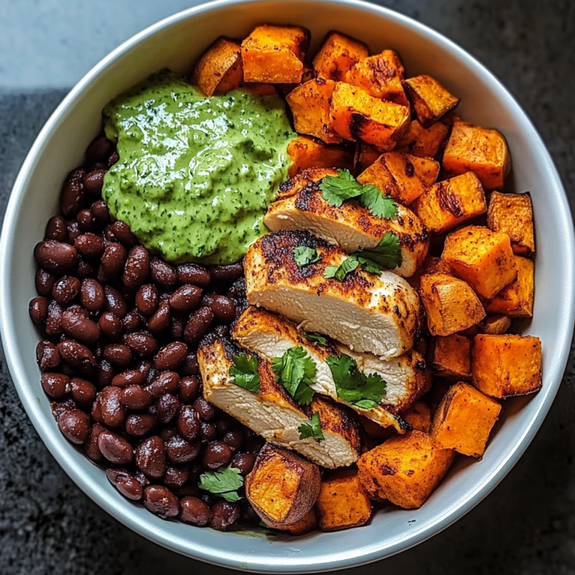 Un bol de nourriture contenant des chips de poulet, des pois noirs, des papas douces et du coriandre.