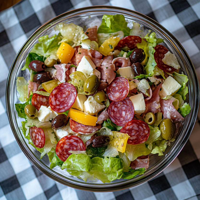 Une salade de charcuterie avec des légumes tels que des tomates, des concombres et des olives.