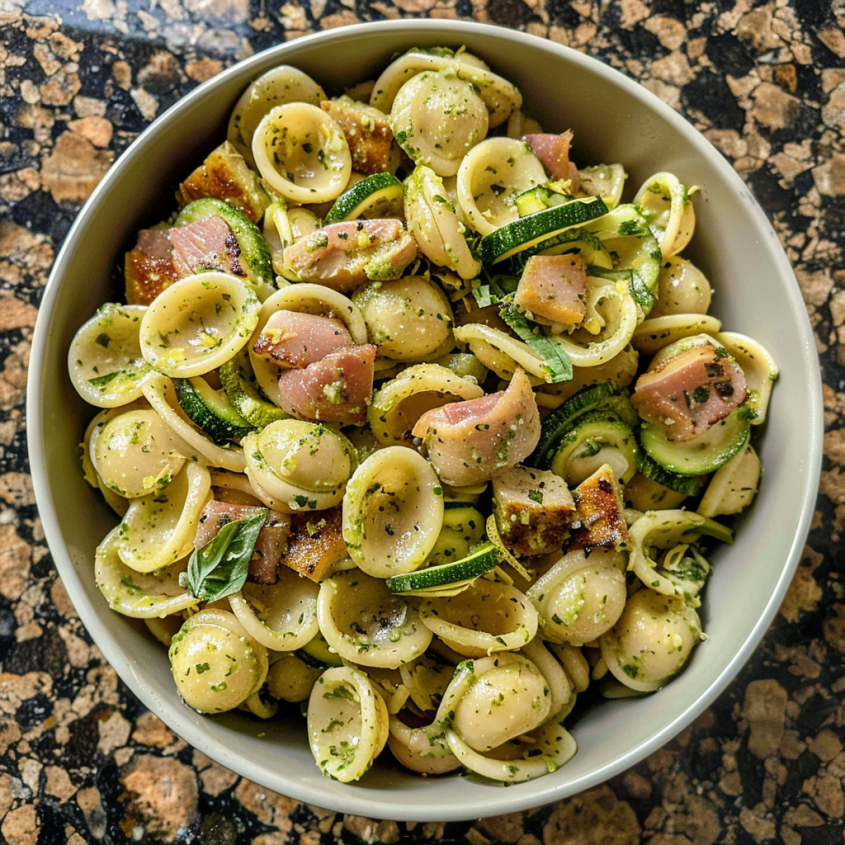A bowl of pasta salad with chicken, zucchini, and basil.