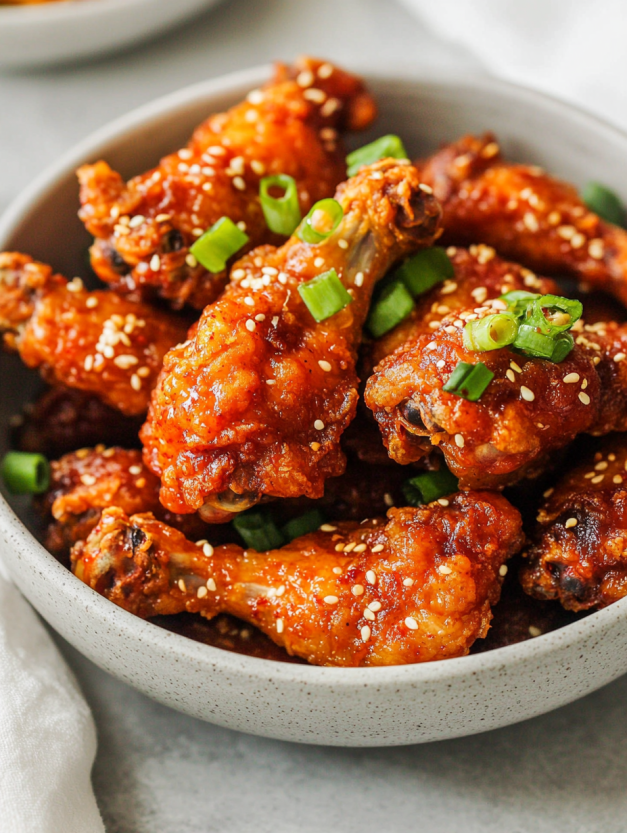 A bowl of chicken with green onions and sesame seeds.